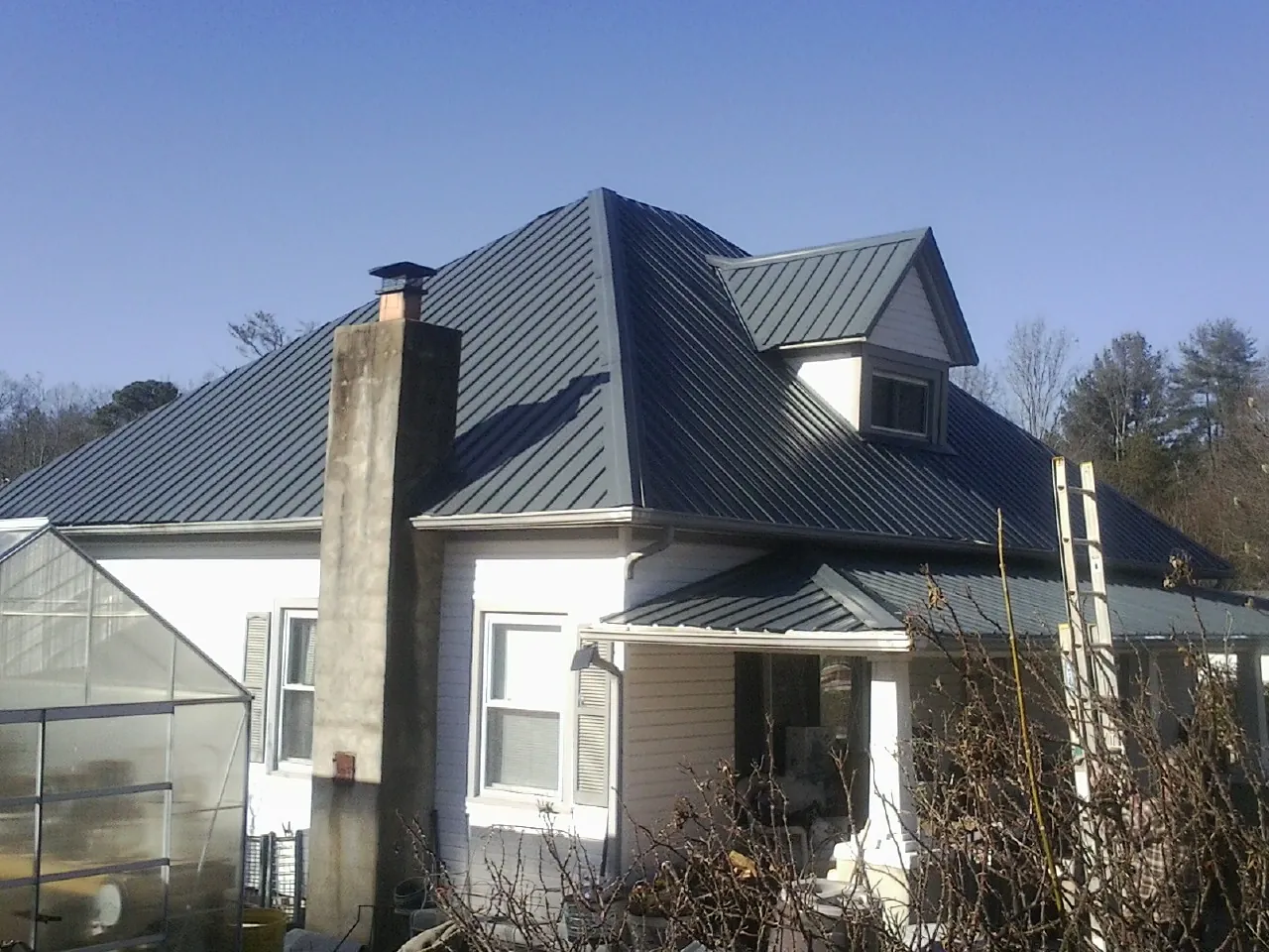 Dark blue standing seam metal roof on a white farmhouse with dormer — Slate & Tile Roof Repair by Roofing Brothers in Singers Glen