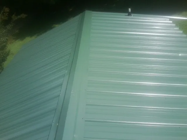 New green metal panels meeting at the ridge of a roof — Flat Roof Repair work by our crew in Singers Glen