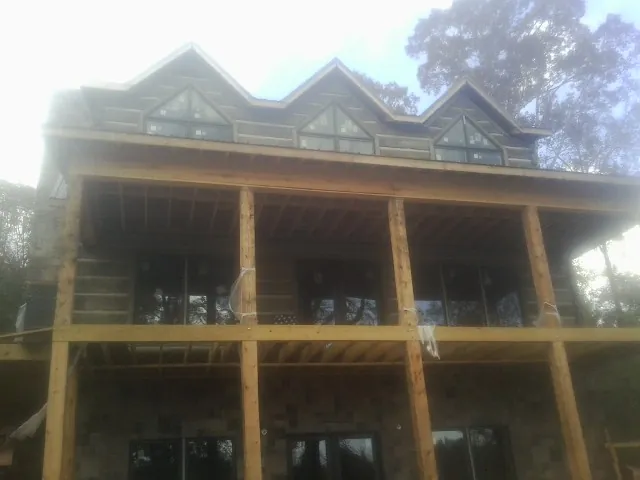 Dormers and porch framing on a large log home under construction — Roof Coating work by our crew in Singers Glen