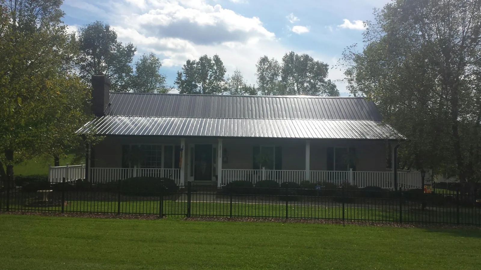 Gray metal roof on a brick ranch with a full width front porch — Gutter Guard Installation work by our crew in Singers Glen