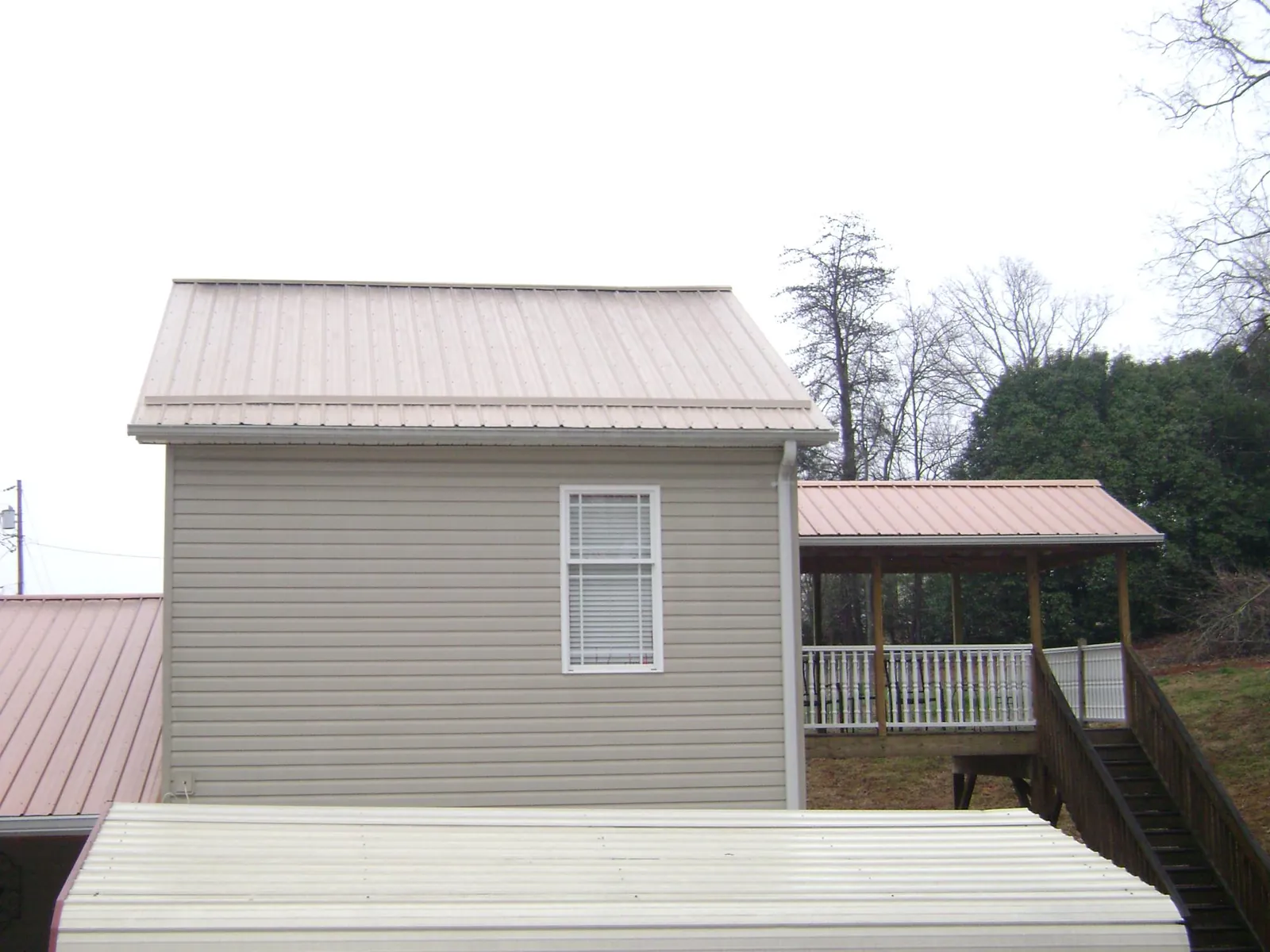 Tan metal roofs on a two story addition and attached porch, from a Roof Replacement job in Singers Glen