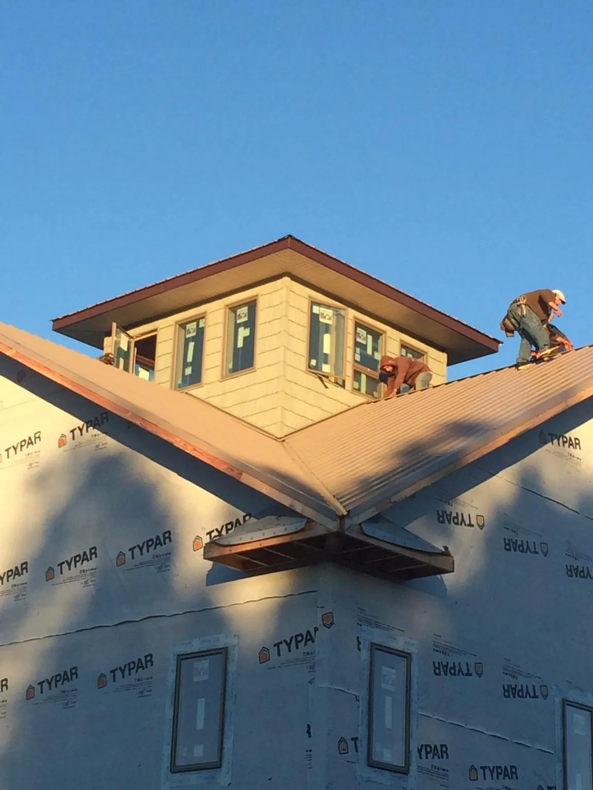 Roofers working around a rooftop cupola on a new metal roof at sunset — Roof Waterproofing in Singers Glen by Roofing Brothers